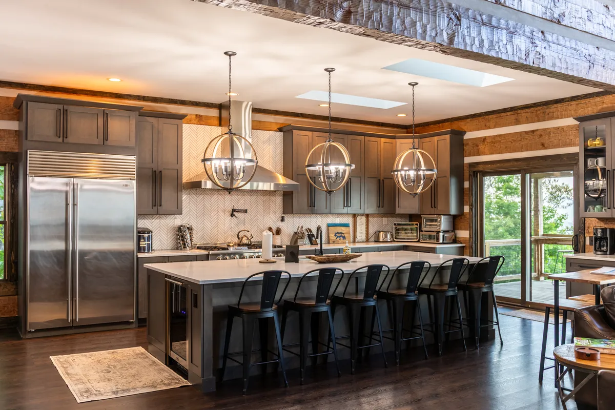 A modern kitchen with a large central island featuring seating, pendant lighting, and stainless steel appliances. Generous windows brighten the space, making it ideal for cooking, entertaining, and informal meals while enjoying views of the outdoors.